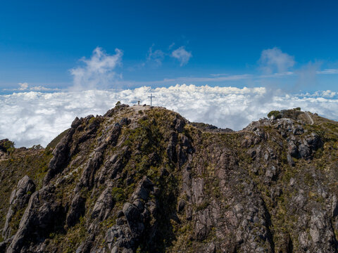 Volcan Baru summit in Chiriqui, Panama, with a white cross and people enjoying the panoramic landscape view above a sea of white clouds under a blue sky - stock photo