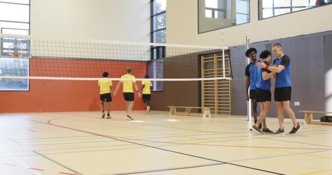 Blue male trio rallying in gym, spiking volleyball at net, celebrating point, resetting, copy space