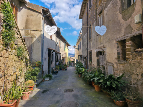 Picturesque narrow alley in Marta village, Bolsena Lake, decorated with hearts and plants, Italy