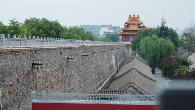Old city defenses. Ancient defensive construction featuring city wall and watchtower surrounded by greenery. Historical stone barrier with sentry tower and lush foliage forming protective enclosure