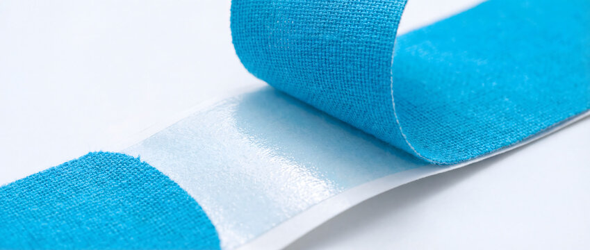Blue kinesiology tape roll with adhesive backing on white surface