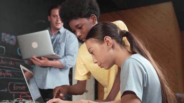 Group of diverse student working together to write program. Multicultural children coding or programming program while teacher pointing at screen at explain mistake point at STEM class. Edification