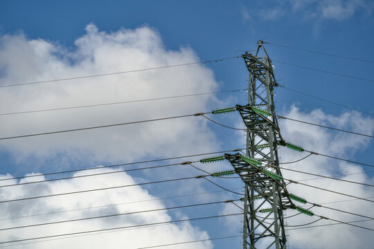 High-voltage transmission tower with power lines against a blue cloudy sky, Dutch electricity grid infrastructure for energy transition