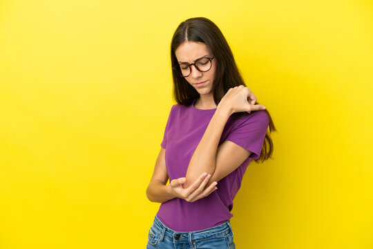 Young French woman isolated on yellow background with pain in elbow