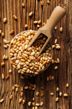 Pine nuts in a bowl with a wooden spoon, top view