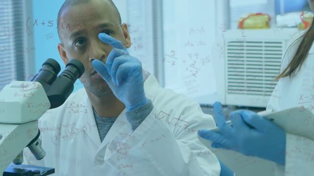 Adjusting microscope man examining sample to report, labcoats, blue gloves, peer noting clipboard