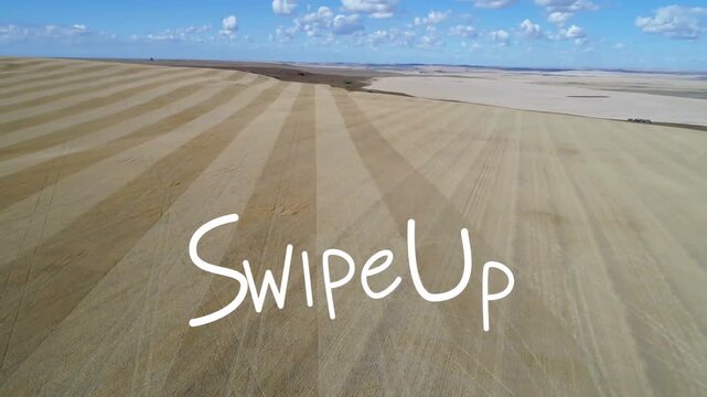 Pulling back drone camera revealing patterned crop rows at open farmland, with white Swipe Up arrow