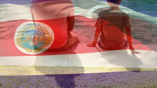 Adult male and child sitting poolside, waving flag overlay revealing coat of arms for marketing