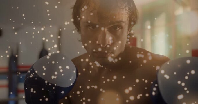 Camera closing in, male boxer keeping guard and practicing jabs in boxing ring, particles drifting