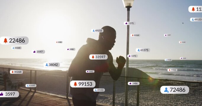Mid adult man in dark hoodie training, throwing jabs along seaside railing, UI badges accumulating