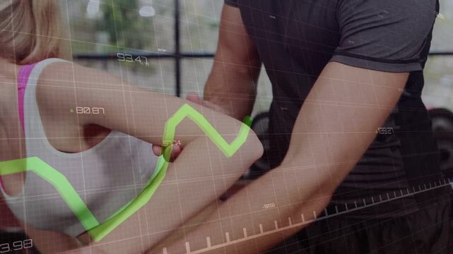 Guiding woman in gym wearing sportswear with dumbbell, trainer placing hands aligning elbow overlay