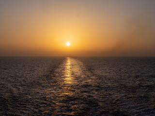 Fototapeta premium Golden sunsetting sun reflecting on ocean water trail