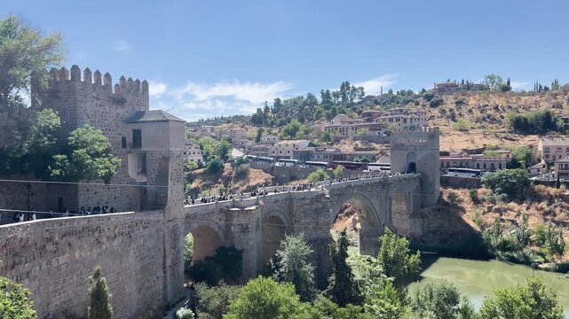 Panoramic view of the historic San Martin bridge with tourists crossing the Tagus river in Toledo