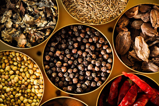 Indian spice box with assorted whole spices top view, masala dabba with black pepper, coriander, bay leaves, cumin, star anise and red chilli close up, black pepper, Kali mirch