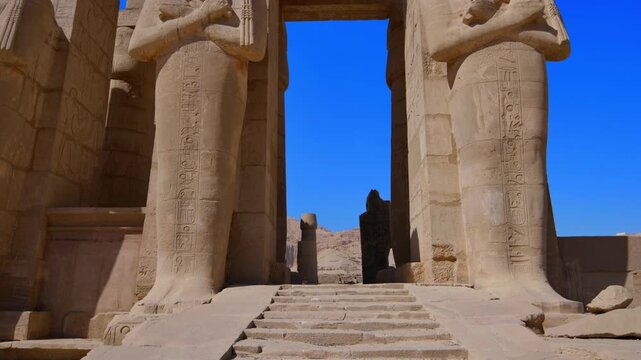 Ruins of Ramesseum mortuary temple with giant Ramesses II Osiride statues. Upward view of massive carved columns and hieroglyphic lintels at Ramesseum temple Luxor Egypt.
