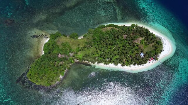 Bird's eye aerial view of Basul Island in Surigao with white sand shoreline and coral shallows in steady clockwise rotation