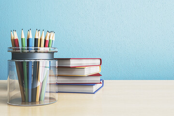 Fototapeta premium Pencil holder filled with colorful pencils beside neatly stacked books on a desk against a light blue wall forming a clean study workspace scene. 3D Rendering