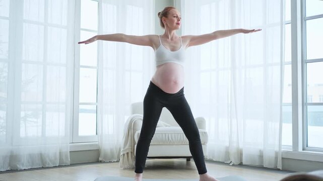 Pregnancy yoga fitness workout training. Pregnant woman practicing yoga at home. Pregnant girl doing sports exercise on yoga mat indoor. Woman with big belly have fitness training practicing asana