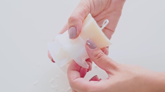 Close-Up of Hands Removing White Candle Wax From Mold During DIY Candle Making Craft Project