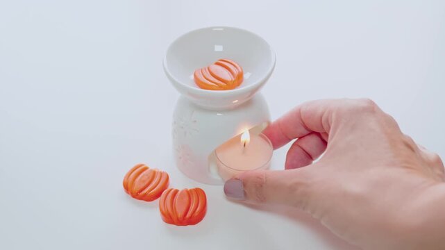 Hand Lighting Tealight Candle Next To Ceramic Wax Melts Oil Burner For Aromatherapy And Relaxation