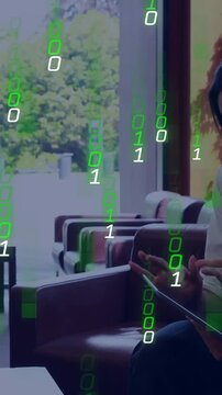 Vertical video: Woman using tablet in lobby, cam showing her green 1s and 0s falling, checking data