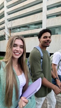 Group of happy young university students walking together and vlogging on campus. Cheerful friends enjoying their college life outdoors