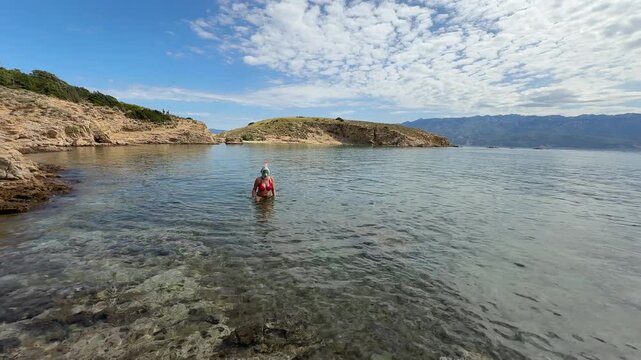 A woman in a swimming mask swims in the Adriatic Sea off the coast of the island of Rab in Croatia, near the town of Lopar,
