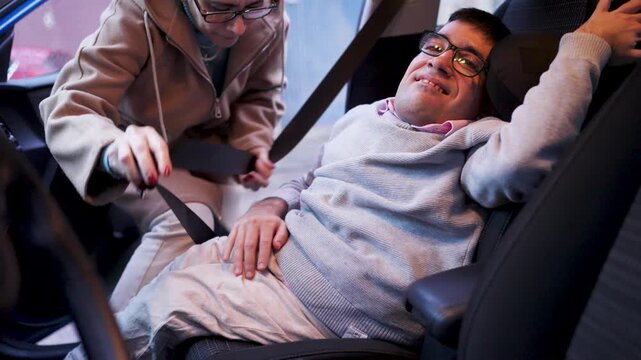 Caring mother assists her son, who has a physical difference, to fasten his seatbelt in the car, showing love and everyday support