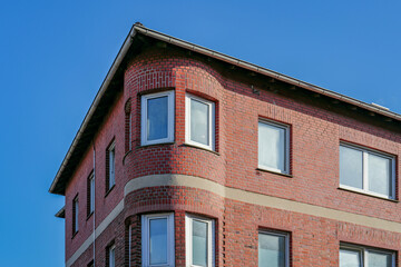 Fototapeta premium Red brick building facade with bay windows against blue sky