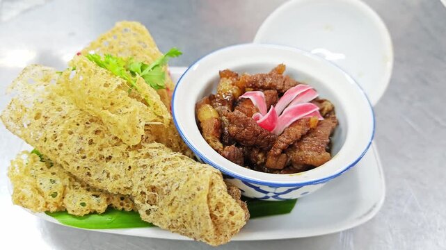 Traditional Thai Appetizer, La Tiang (Egg Net Wrapped Minced Pork), served with sweet savory pork and fresh chili garnish.
