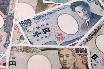 Japanese yen money bills pile on table. Japan banknotes of JPY currency close up. © Larysa