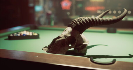 A striking skull with curved horns rests on a green felt pool table, while a set of billiard balls awaits in the background, enhancing the bars unique ambiance late at night. © icetray