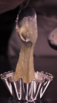 A female baker prepares cupcakes using a pastry bag. Vertical video about homemade pastries, cooking and confectionery.