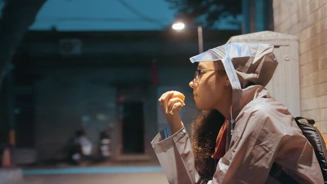 Night skyward gaze asian woman contemplative, hood up and backpack slung, eyes lifted toward streetlight and distant stars, quiet alley stillness with soft blue tones and nostalgic cinematic feel