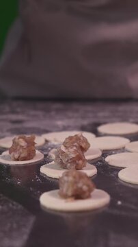 A woman cooks dumplings with meat filling. Vertical video.