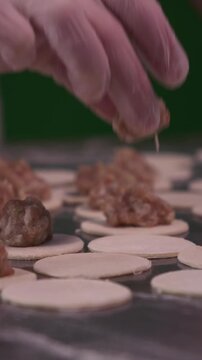 A woman cooks dumplings with meat filling. Vertical video.