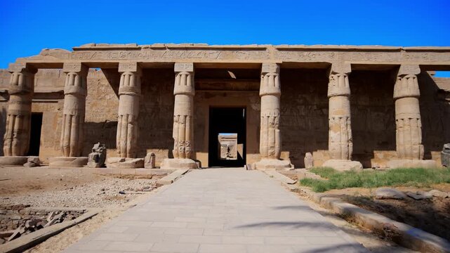 Seti I mortuary temple entrance with palm tree alley and ancient stone ruins in Luxor Egypt. Scenic pathway under vivid blue sky.