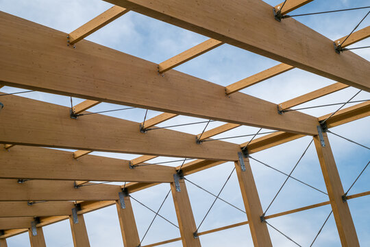 Detail of a modern wooden architecture in glued laminated timber on a blue cloudy sky