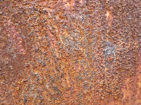 Heavily corroded rusty iron metal surface texture background with orange brown oxidation and peeling layers