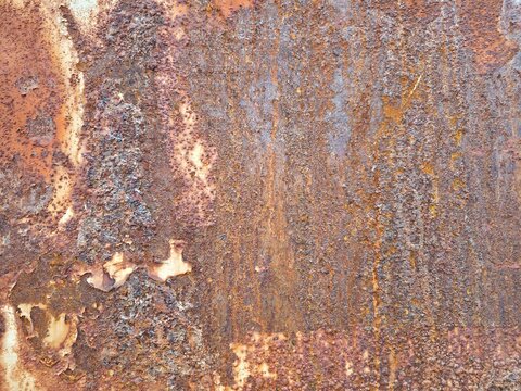 Rusty corroded metal surface texture with peeling paint and streaked orange brown oxidation pattern background