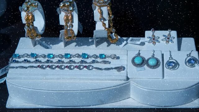 Sivler and gold bracelets, necklaces and earrings inlaid with precious stones like ruby, turquise and amethyst crafted in traditional Indian style with floral patterns are displayed on the store count