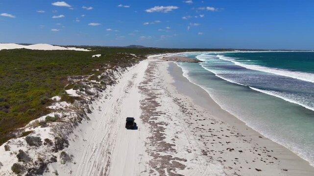 Aerial drone view of a 4WD vehicle with a rooftop tent driving along the coastline near Esperance, Western Australia.