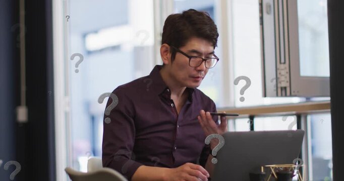 Animation of question marks over asian businessman working at office