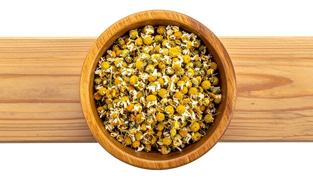 Close-up of dried chamomile flowers filling a wooden bowl placed on a light-brown wooden surface, isolated on white