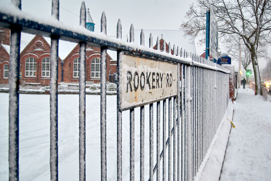 Snow on metal railings and Rookery Rd street sign with Rookery School building in the background, Handsworth, Birmingham, West Midlands, England, UK.