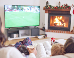 Obraz premium Experience festive domestic bliss as a family watches soccer by a warm fireplace. This cozy holiday scene captures the true essence of winter togetherness and seasonal home entertainment.