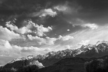 Obraz premium B&W photography,Ancient Stone Castle ruins overlooking snow-capped Pamir peaks, under a dramatic sky, a Silk Road landmark linked to Xuanzang, Journey to the West, along the KKH.