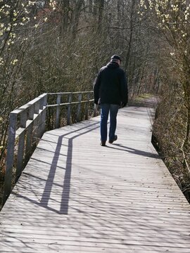Mann von hinten geht &uuml;ber Holzbr&uuml;cken