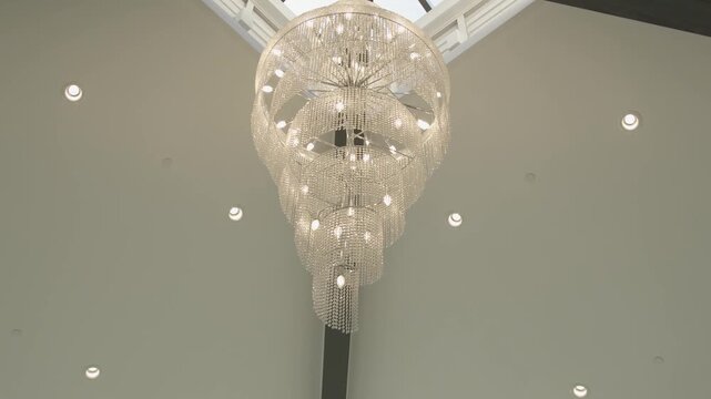 Elegant crystal chandelier hanging from high ceiling in modern interior design with glowing lights