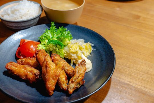 黒い丸皿に唐揚げとサラダが盛られた定食